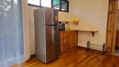 a stainless steel refrigerator in a kitchen next to a window at Susanne's Bungalow de Casa Felicidad in Paquera
