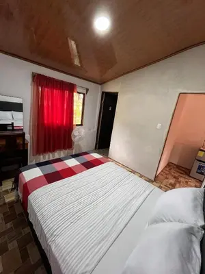a bedroom with a large bed with a red window at Villa Rancho Caballito in Nicoya