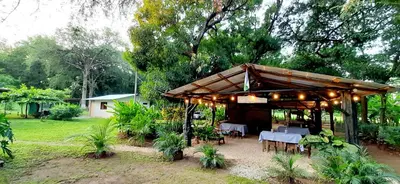 a pavilion with tables and chairs in a garden at Villa Rancho Caballito in Nicoya