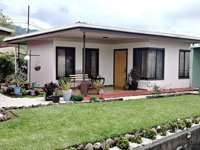 a small house with a lawn in front of it at Hospedaje con relajante Vista in Grecia
