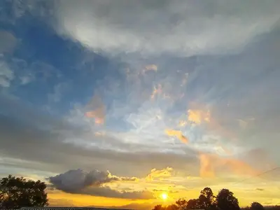a cloudy sky at sunset with trees in the foreground at Hospedaje con relajante Vista in Grecia