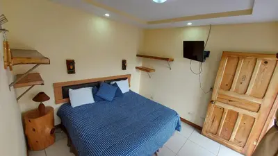 a bedroom with a blue bed and a television at Hotel Orocay Lodge in Cartago