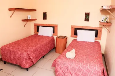 two beds in a hotel room with red sheets at Hotel Orocay Lodge in Cartago