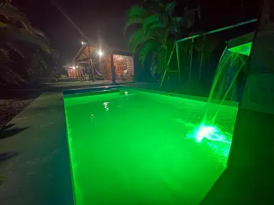a swimming pool with green illumination at night at Cabaña YeyYe in San Ramón