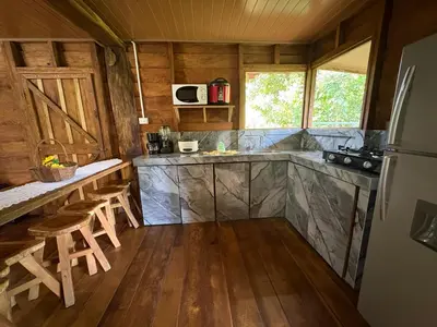 a kitchen with wooden walls and wooden floors and a refrigerator at Cabaña YeyYe in San Ramón