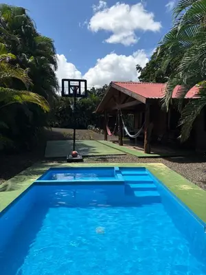 a blue swimming pool next to a basketball hoop at Cabaña YeyYe in San Ramón