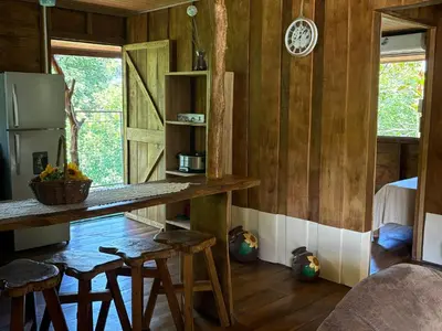 a kitchen with wooden walls and a counter and stools at Cabaña YeyYe in San Ramón