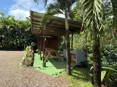 a small wooden cabin with a table and palm trees at Cabaña YeyYe in San Ramón