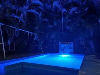 a swimming pool at night with blue lights at Cabaña YeyYe in San Ramón