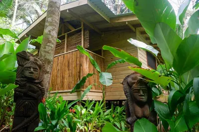 two statues in front of a wooden house at Finca LOS 4 VIENTOS in Savegre