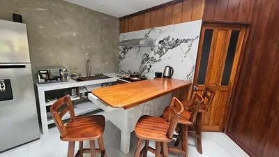a kitchen with a wooden counter and chairs in it at The Hideaway La Fortuna in Fortuna