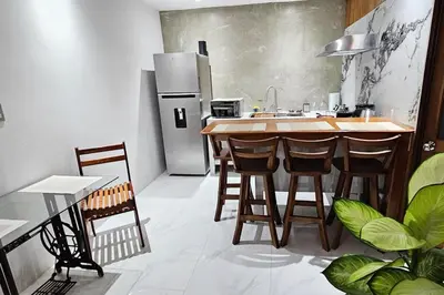 a kitchen with a kitchen island with chairs and a refrigerator at The Hideaway La Fortuna in Fortuna