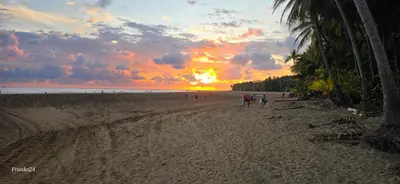 a group of people walking on the beach at sunset at Bahia Ballena Walk to the Beach Uvita Apartments in Uvita