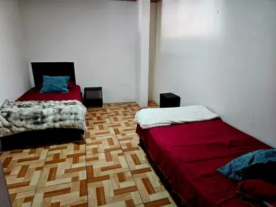a bedroom with two beds and a wooden floor at Hostal Zurgab in San Vicente