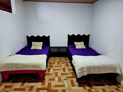 two beds in a room with purple and white at Hostal Zurgab in San Vicente