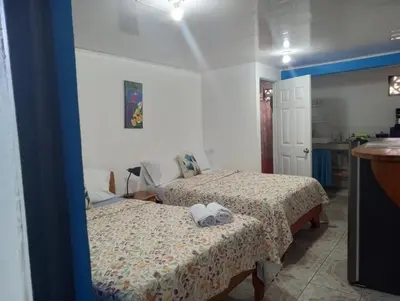 a bedroom with two beds and a kitchen at Cabina Chazu#1 in Quepos