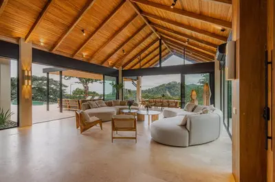 a living room with couches and tables and windows at Bahia Rooms in Mal País