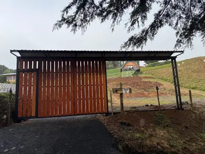 a large wooden gate with a building in the background at Cabaña La Trinidad de Dota in El Copey