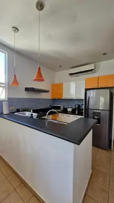 a kitchen with a black counter top and a refrigerator at Villas Portofino in Tamarindo
