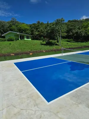 a blue tennis court with a house in the background at 2 Bedroom Guest House with Pool in Hacienda Miravalles