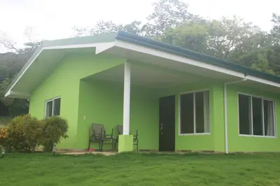 a green house with a porch at 2 Bedroom Guest House with Pool in Hacienda Miravalles