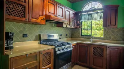 a kitchen with wooden cabinets and a stove top oven at Arenal Tropical Home Villa in Fortuna