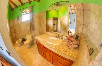 a bathroom with a sink and a toilet and a mirror at Arenal Tropical Home Villa in Fortuna