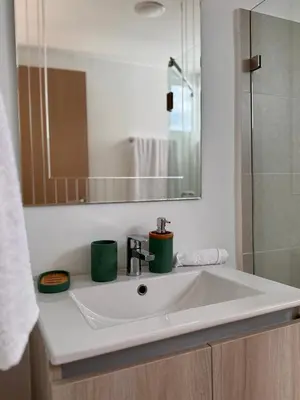 a bathroom sink with two green cups on it at Jacó Pacífico in Jacó