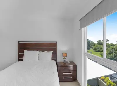 a white bedroom with a bed and a window at Jacó Pacífico in Jacó