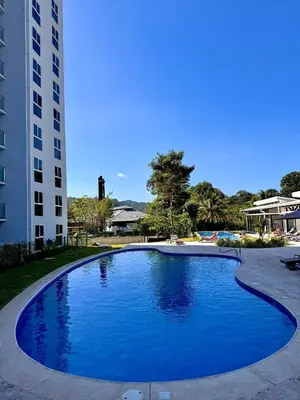 a large blue swimming pool next to a tall building at Jacó Pacífico in Jacó