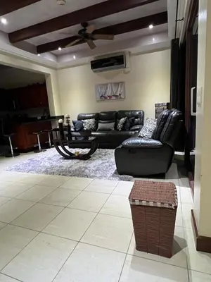 a living room with black leather furniture and a ceiling fan at Condo Roldan macaw 12 Jaco Unique,with access to the sea in Jacó