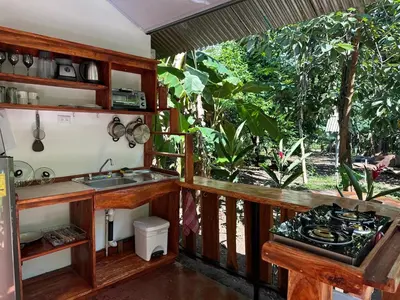 a kitchen with a sink and a stove in a room at Cabañas Playa Cedros in Puntarenas