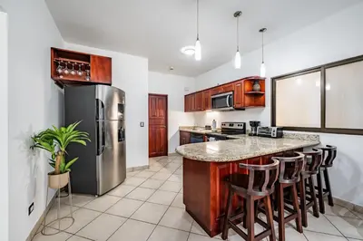 a kitchen with a stainless steel refrigerator and bar with stools at Beautiful Condo, Tamarindo Costa Rica in Huacas