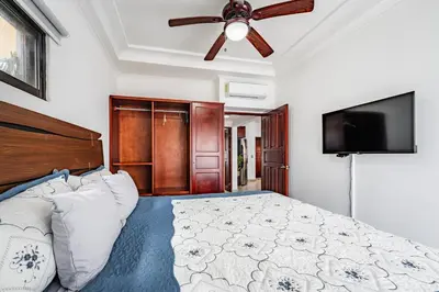 a bedroom with a bed with a ceiling fan and a flat screen tv at Beautiful Condo, Tamarindo Costa Rica in Huacas