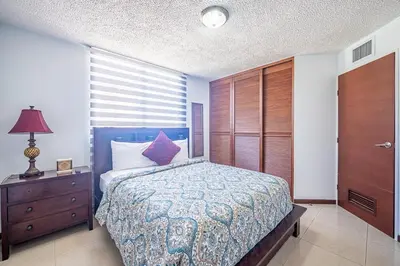 a bedroom with a blue bed and a dresser with a lamp at Beautiful Jaco Apartment CL 1-23 - Just a short walking distance to the beach in Jacó