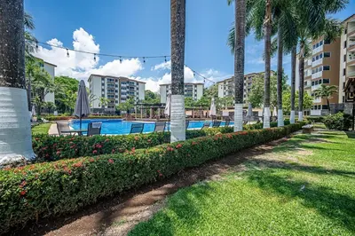 a swimming pool at a resort with palm trees at Beautiful Jaco Apartment CL 1-23 - Just a short walking distance to the beach in Jacó