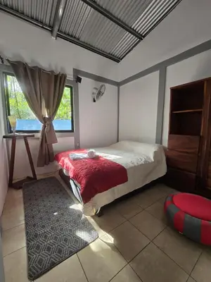 a bedroom with a large bed and a window at Casita el Jardin in Nuevo Arenal
