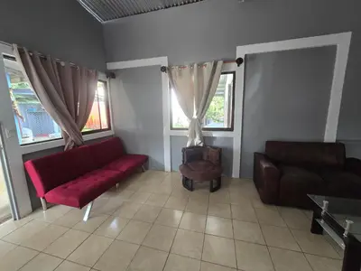 a living room with a red couch and a chair at Casita el Jardin in Nuevo Arenal