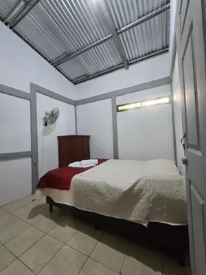 a bedroom with a bed in a white room at Casita el Jardin in Nuevo Arenal