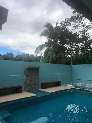 a swimming pool with benches next to a blue wall at Casa Monos in Quepos