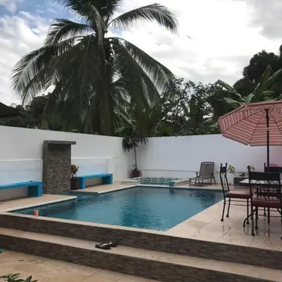 a swimming pool with a table and chairs and an umbrella at Casa Monos in Quepos
