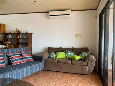 a living room with a brown couch and green pillows at Apartamento equipado, con amplia piscina in Paquera