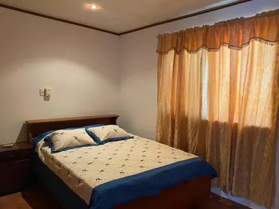a bedroom with a bed and a window with curtains at Apartamento equipado, con amplia piscina in Paquera