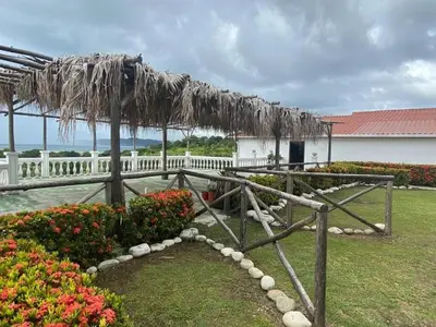 a pavilion with a thatched roof and some flowers at Apartamento equipado, con amplia piscina in Paquera
