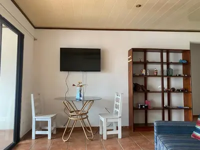 a living room with a table and a tv on the wall at Apartamento equipado, con amplia piscina in Paquera