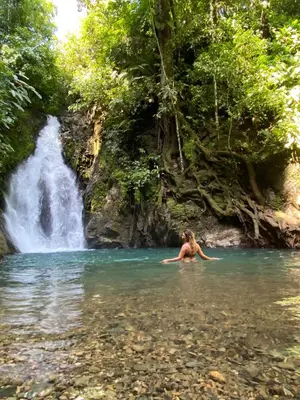 a woman swimming in the water in front of a waterfall at Private room in nature in Coronado