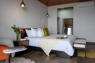 a bedroom with a bed with white sheets and yellow pillows at ÉWA Homes Monteverde in Monteverde Costa Rica
