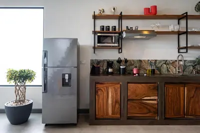 a kitchen with a stainless steel refrigerator and wooden cabinets at ÉWA Homes Monteverde in Monteverde Costa Rica