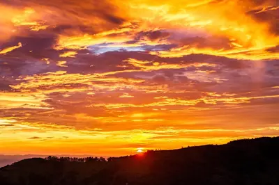 a sunset with the sun setting over a mountain at ÉWA Homes Monteverde in Monteverde Costa Rica