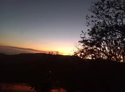 a sunset over a hill with a tree in the foreground at Cabina el atardecer in Monteverde Costa Rica